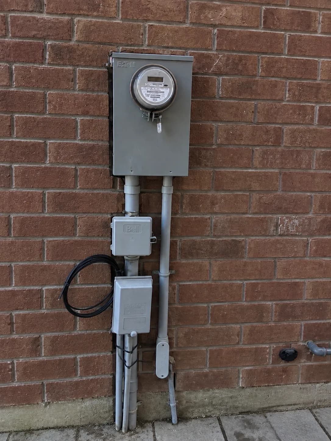 A meter socket on a brick wall with two disconnects and the conduit run landed below it.