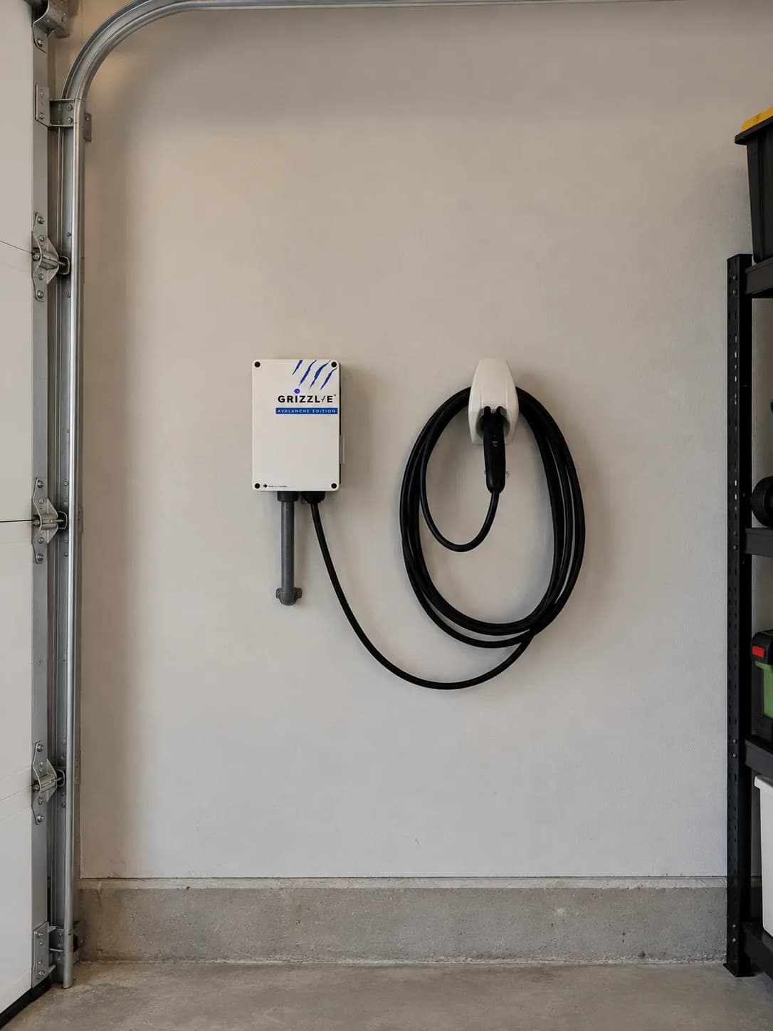 A Grizzl-E Level 2 charger Copper Bee installed on a garage wall in Toronto, its connector on the holster, the cable coiled and the conduit dropped from the enclosure.