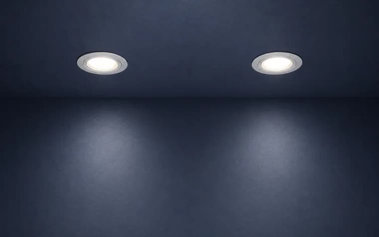 Two recessed pot lights washing light down a finished wall.